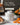 White Linen Butter Bell® Crock with raised floral detail beside bread and citrus on a breakfast table