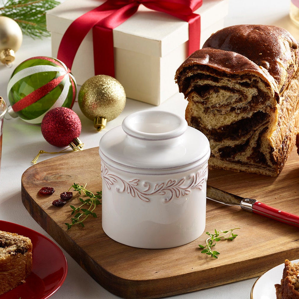 Christmas-themed table setting with pastries, tea, and coffee on a white tablecloth. butter bell crock